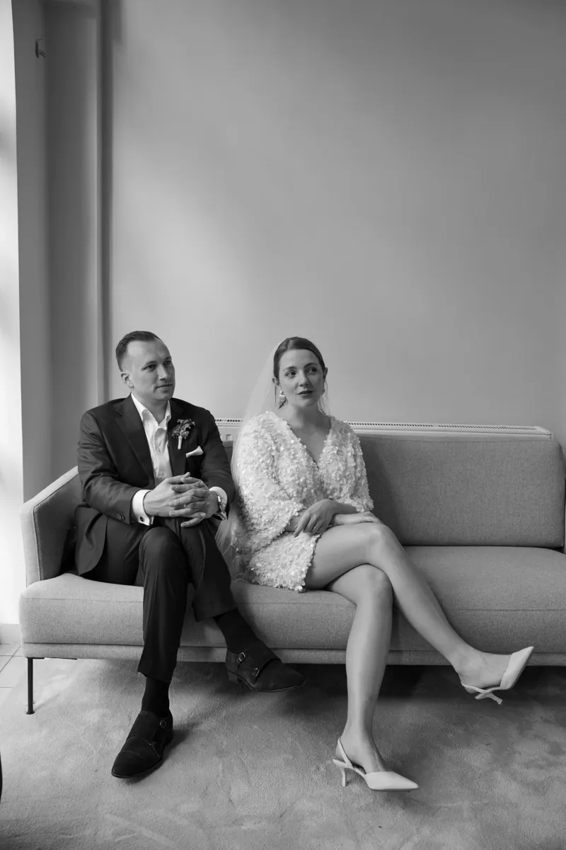 Brautpaar sitzt auf Sofa in eleganter Hochzeitskleidung